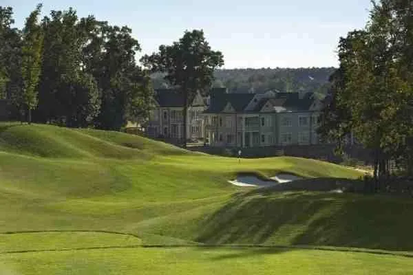 A fairway at Grand Oaks running below a row of clubhouse buildings, with bunkers cut into the slope.