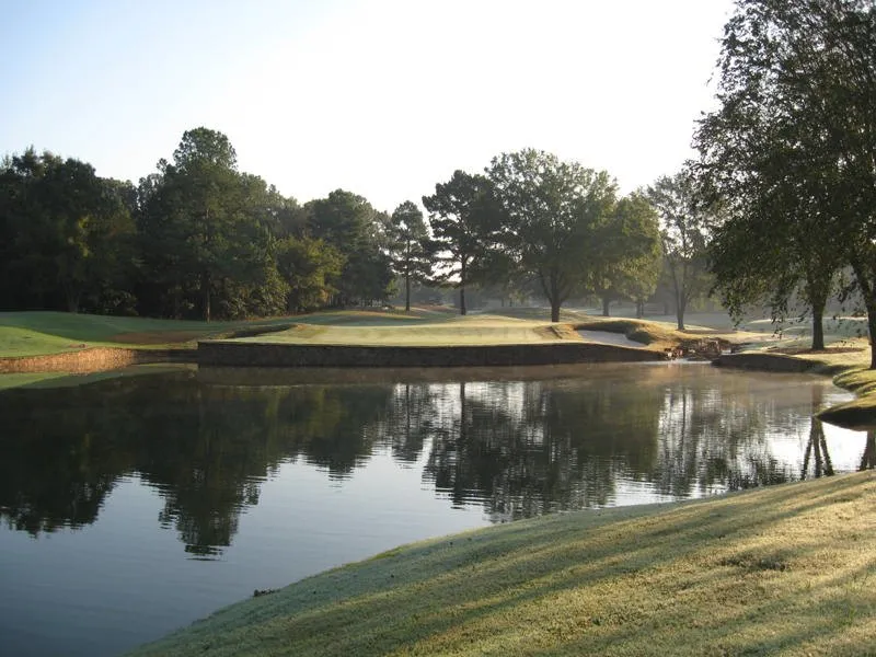Morning mist over a lake at Mirimichi, with a bunkered green on the far bank mirrored in the water.